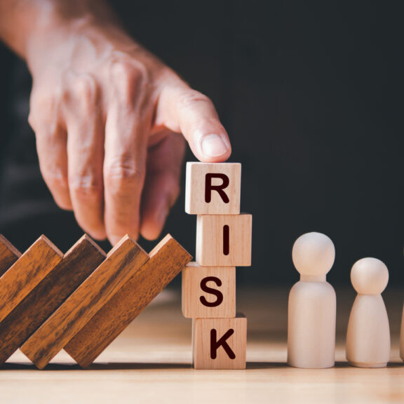 Financial Crisis, Economic, Business Risk Management Concept. Risk word on wooden block, domino effect falling to family. Concept Risk, Crisis, Management, Assessment, Insurance, Security, Finance